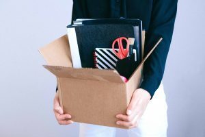 woman carrying cardboard box of office supplies